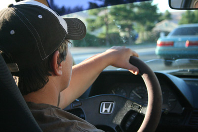 teenage boy driving, hand on steering wheel
