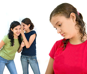 2 teenage girls talking behind another teenage girl