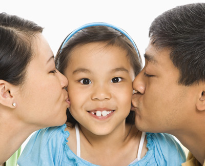 girl being kissed by her mom and dad