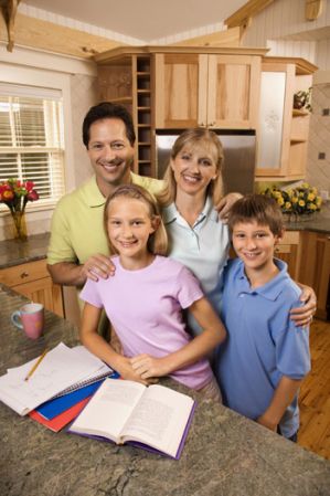 mother and father with son and daughter in the kitchen doing homework